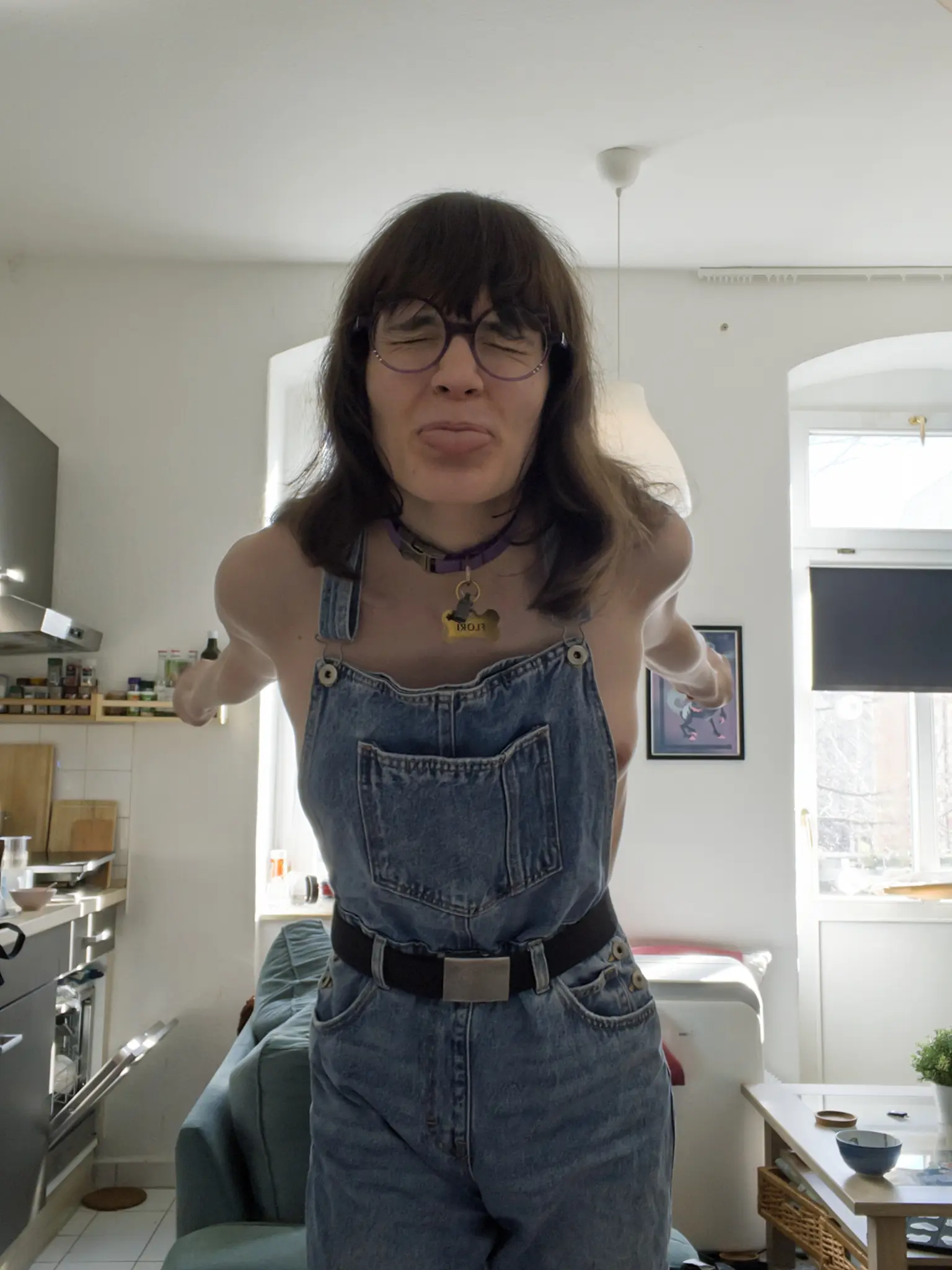 Same as before, but Ava is sticking their tongue out at the camera, eyes closed and both arms stretched out backwards, as she is leaning forwards a little