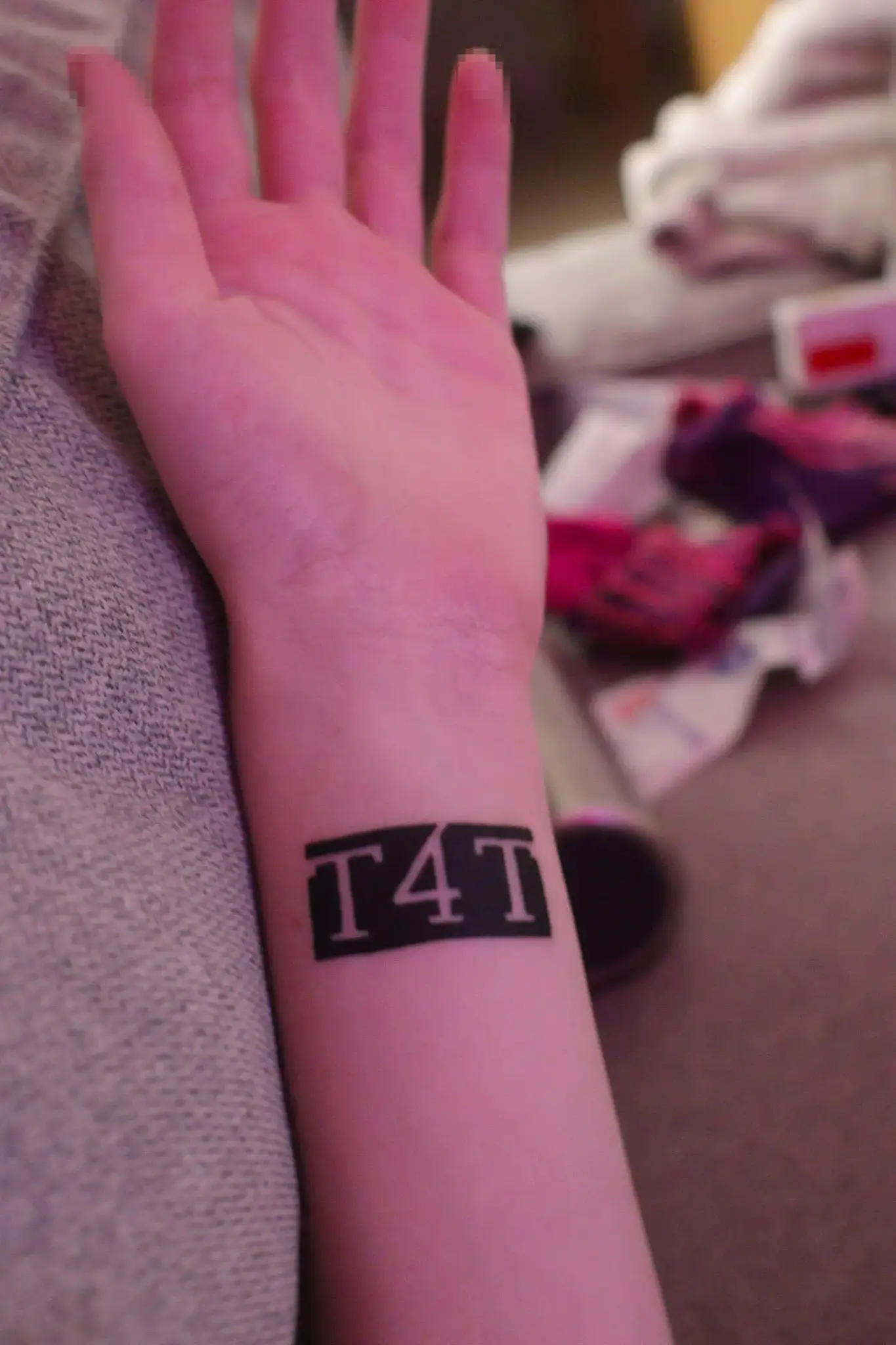 my paw with t4t tattooed on the wrist. there's a little mess on the background, it's a couch my paw with t4t tattooed on the wrist. there's a little mess on the background, it's a couch