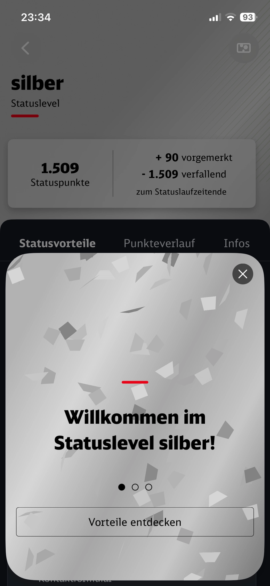 Screenshot of a dark-themed mobile app in German, showing a "silber" (silver) status level page with 1.509 Statuspunkte (status points), +90 points reserved and -1.509 expiring at the end of the status period. A light grey modal popup overlaid on the screen shows scattered grey paper confetti pieces and the bold text "Willkommen im Statuslevel silber!" with a small red horizontal line above it, three pagination dots, and a button labeled "Vorteile entdecken" at the bottom.