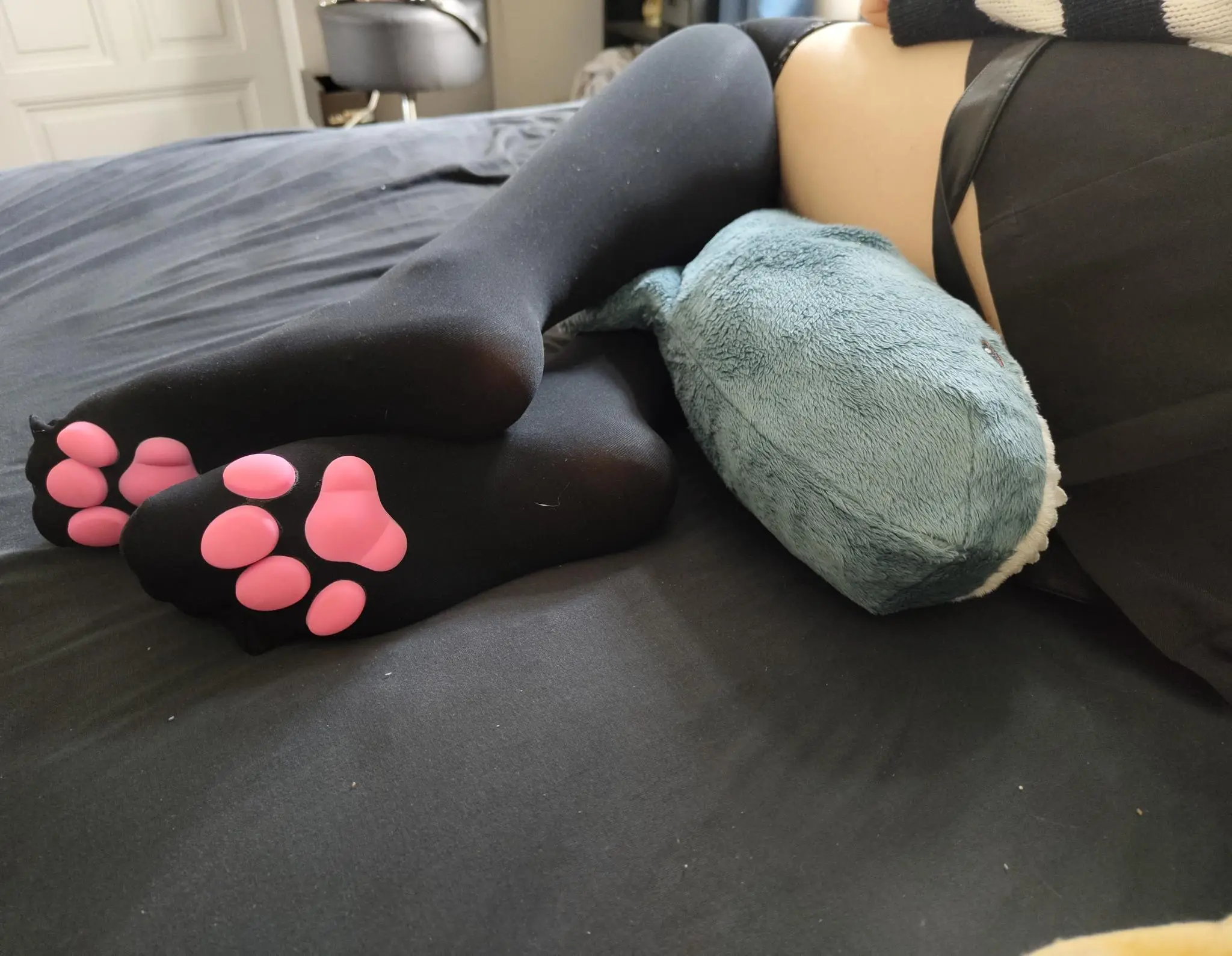 closeup of ellies feet wearing cat paw stockings on a grey bedsheet